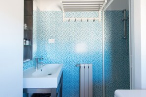 Une salle de bain avec un lavabo blanc, une cabine de douche en verre et un mur carrelé.