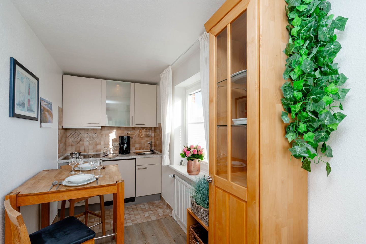 A compact kitchen with a dining table, a coffee maker, and a potted plant.