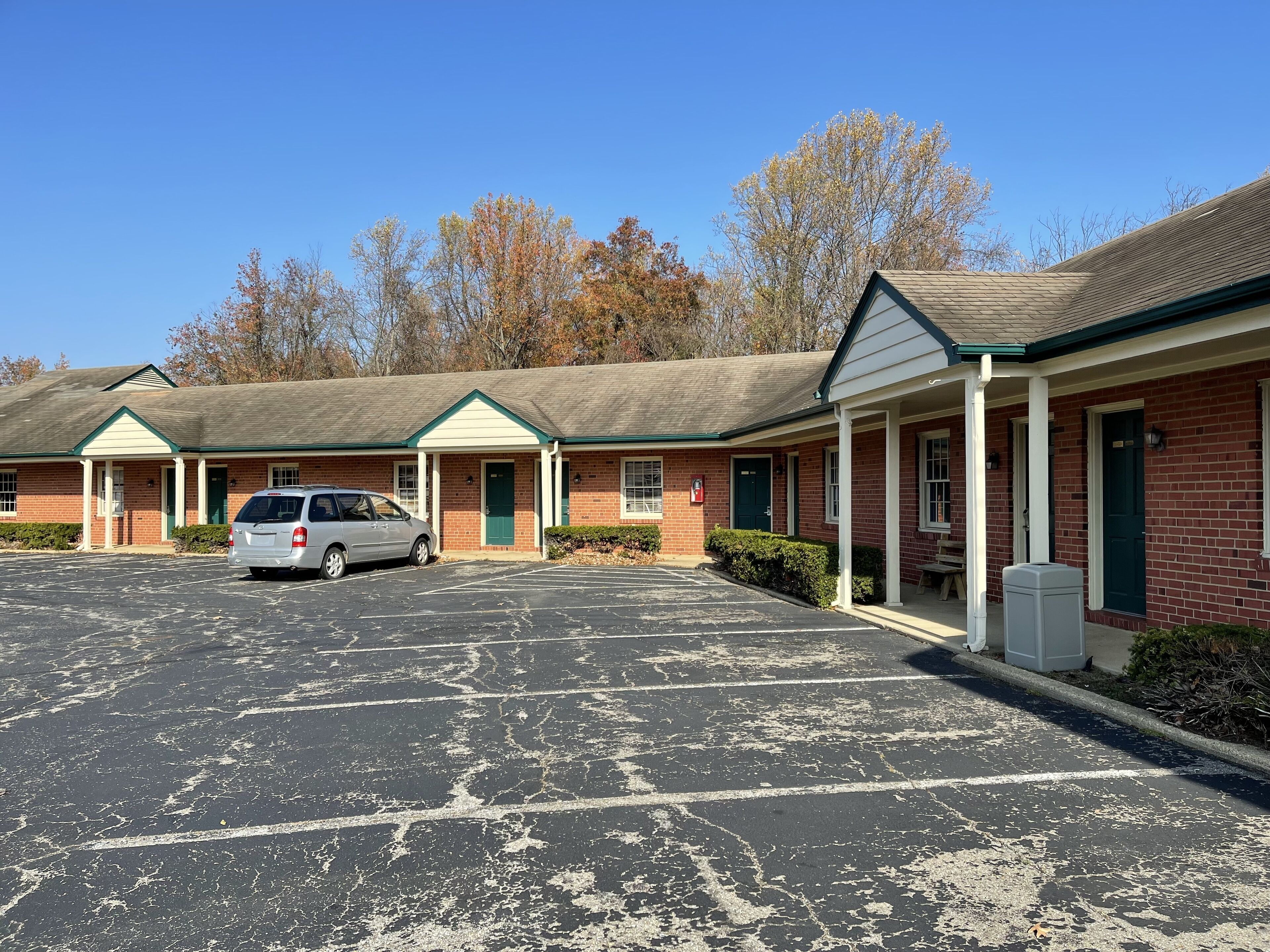 A motel with a parking lot and a single car parked in front.