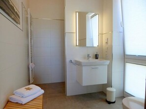 Un baño moderno con ducha, lavabo con espejo e inodoro.