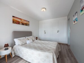 Un dormitorio con cama, mesitas de noche, un armario y un cuadro en la pared.