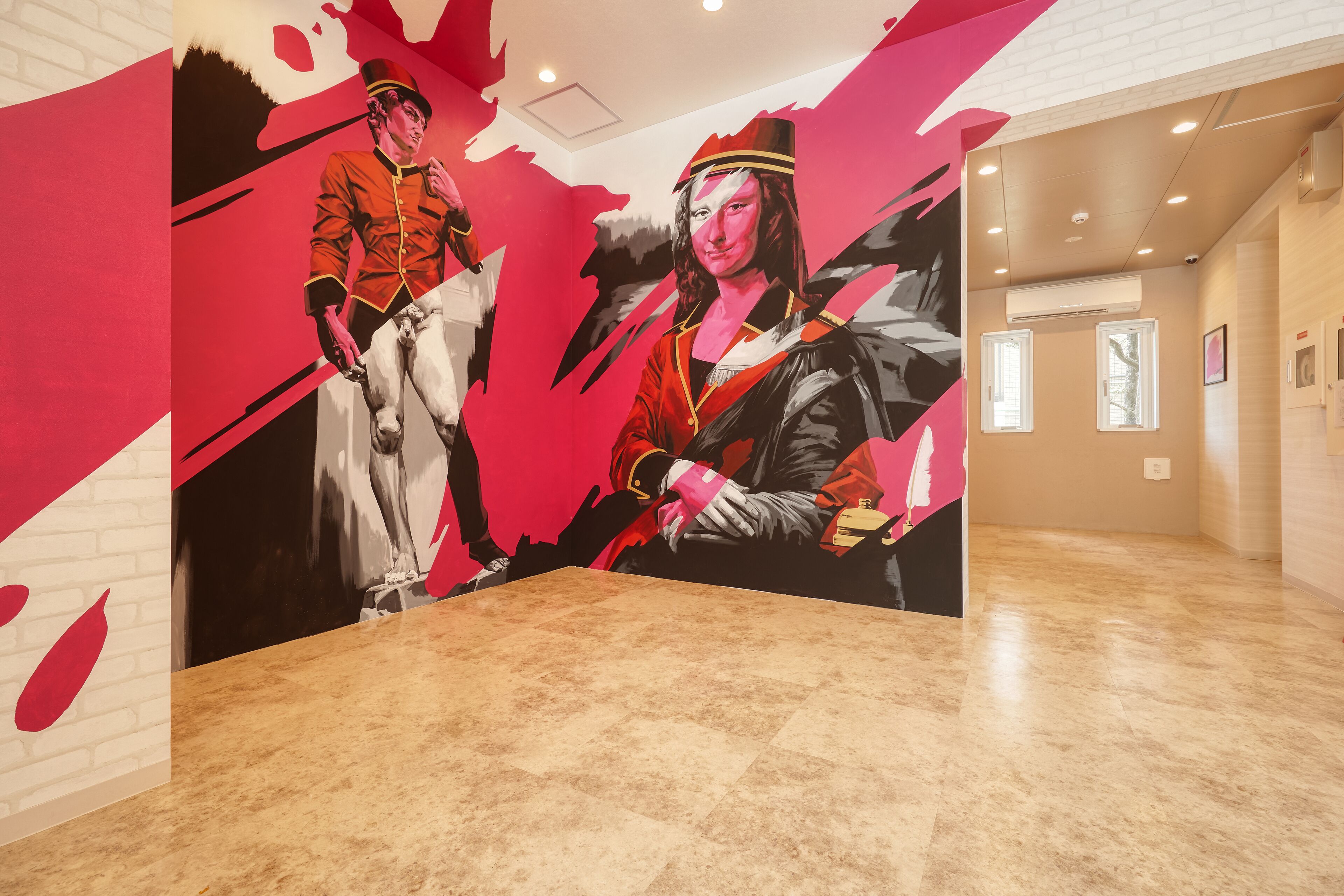 Una habitación con un gran mural de dos figuras vestidas con trajes de época, suelo de madera y una pared lisa con una ventana.