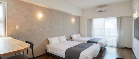 A modern hotel room with two beds, a wooden table, and a chair.