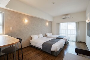 Quarto de hotel moderno com duas camas, uma mesa de madeira e uma cadeira.