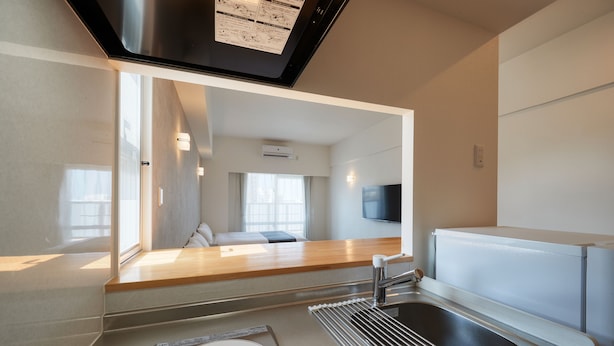 A modern kitchen with a built-in stove, a sink, and a window. - New Normal Hotel in NAMINOUE (Naha)