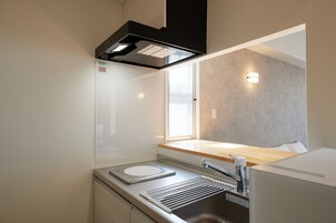 Uma kitchenette compacta com forno embutido, pia e janela que proporciona iluminação natural.