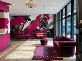 Um hall moderno com um grande mural, móveis vermelhos aconchegantes e um lustre.