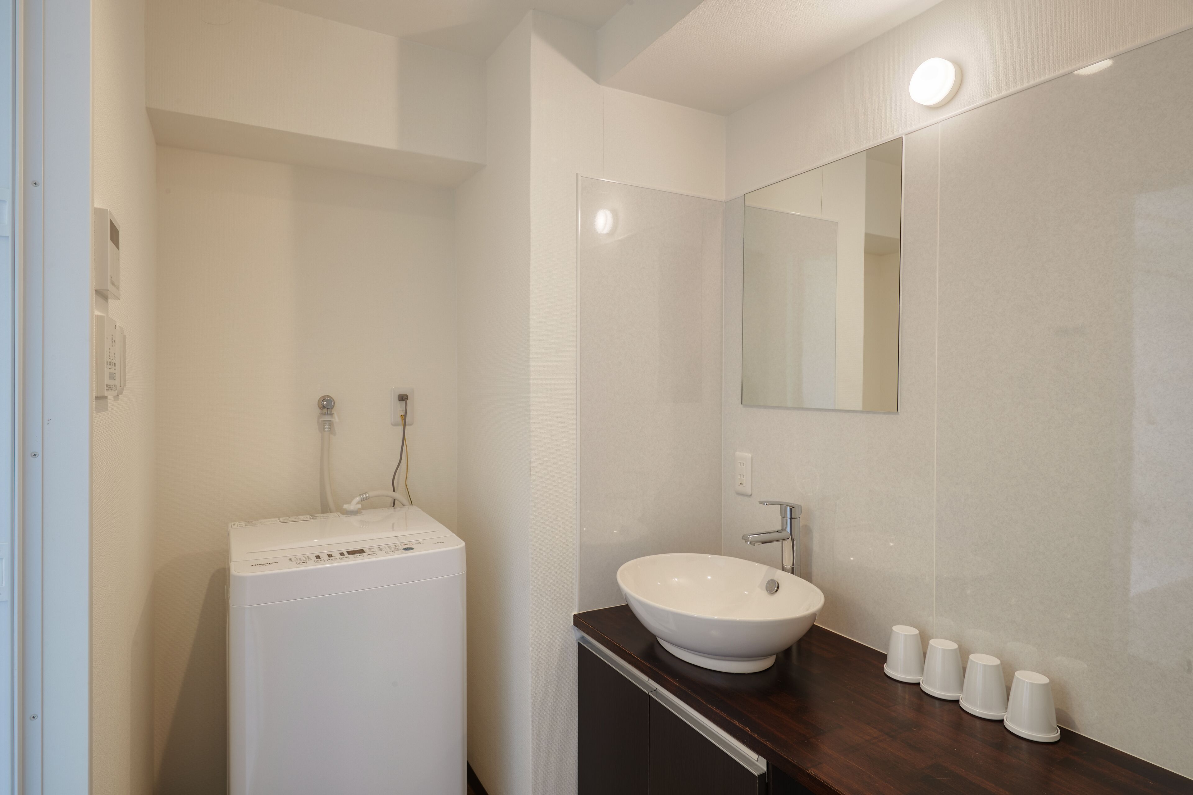 Un baño moderno con lavadora blanca, lavamanos y espejo.