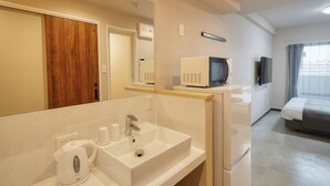 A hotel bathroom with a sink, mirror, and a microwave on a countertop. - New Normal Hotel in MATSUYAMA (Naha)