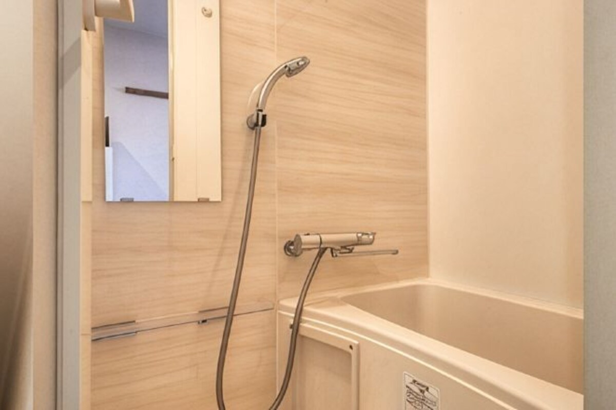 A bathroom with a shower, a mirror, and a bathtub.