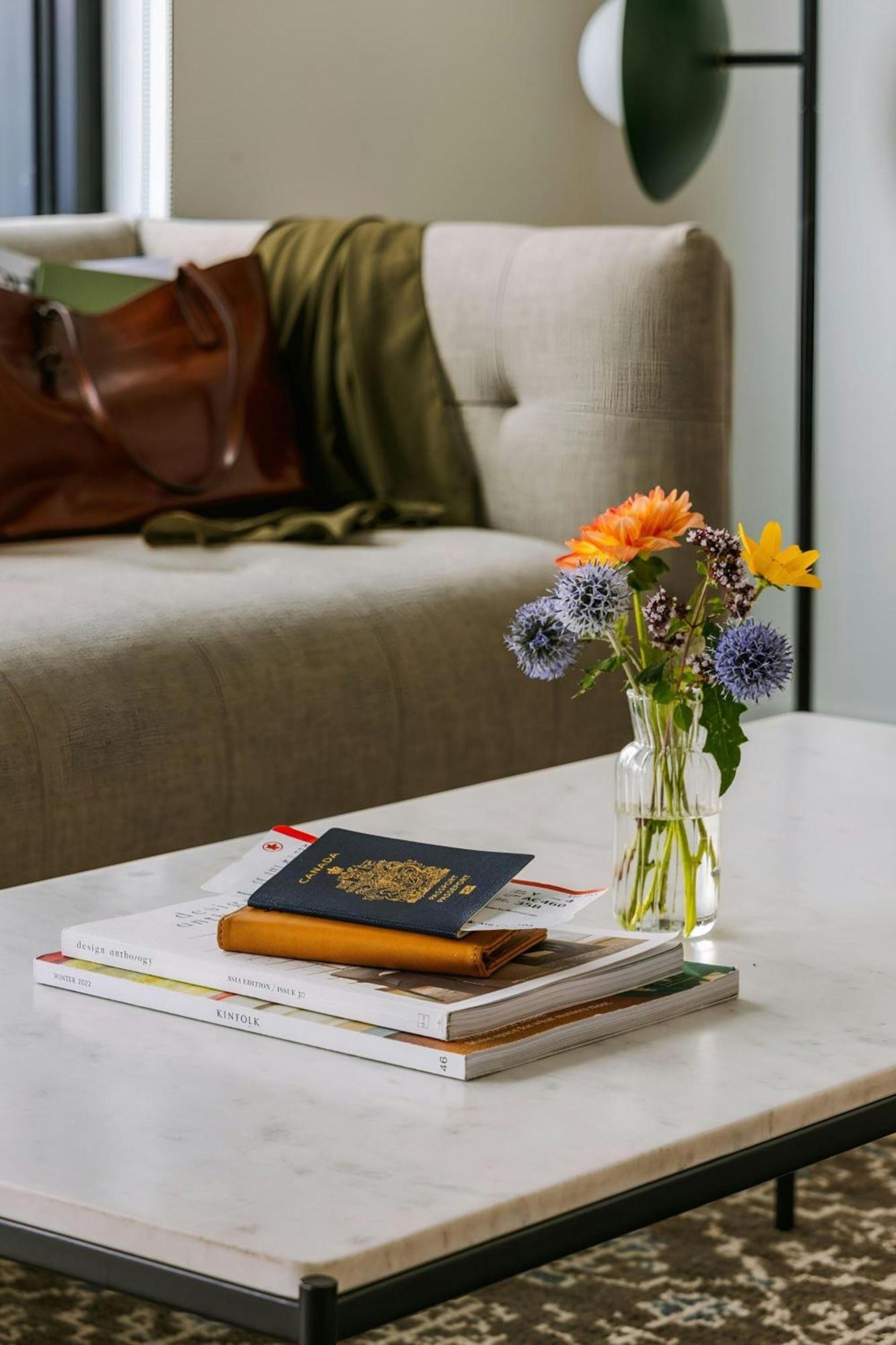 A room with a sofa, a coffee table with books and a vase of flowers.