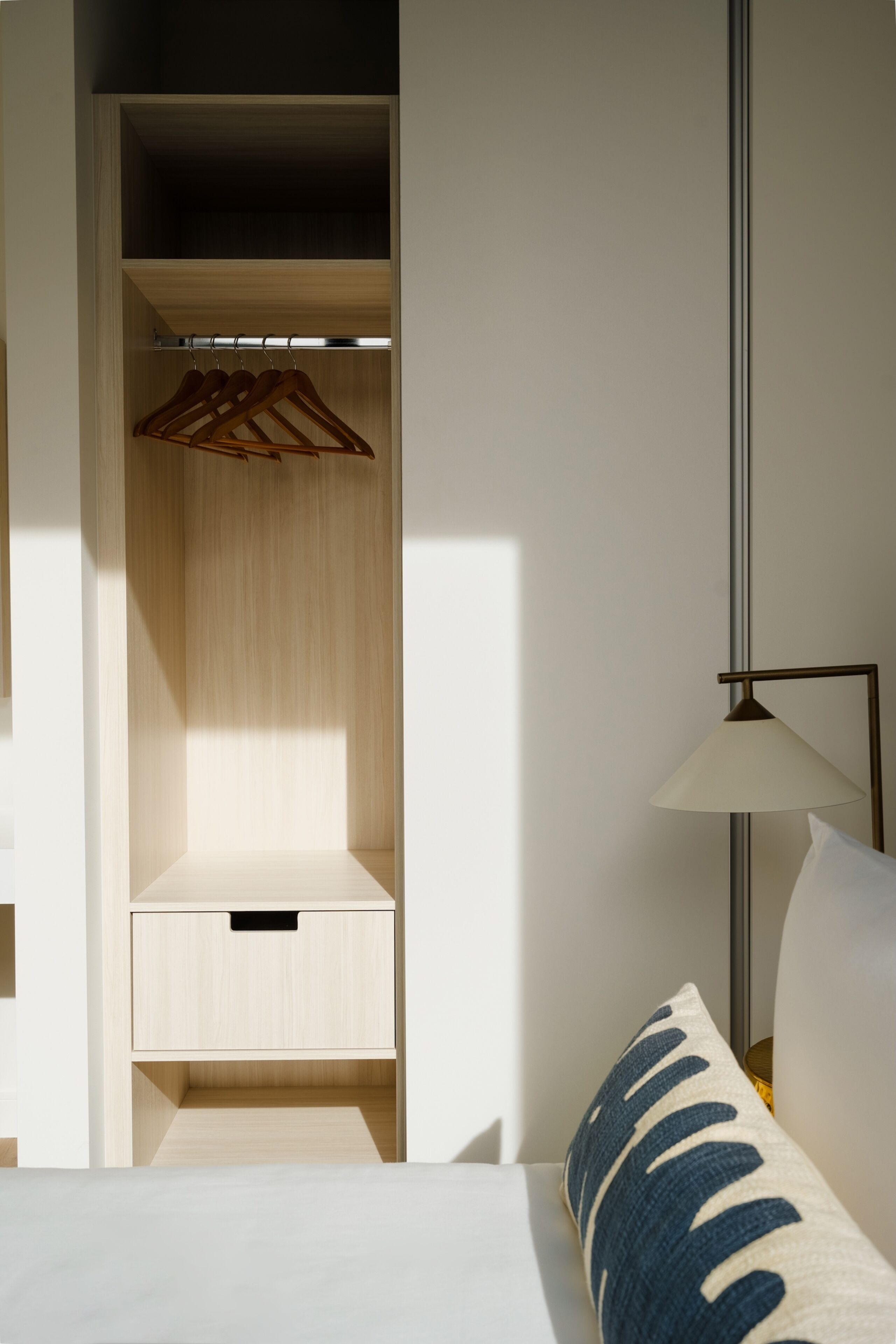 Une chambre d’hôtel comprenant un lit, une table de chevet, une lampe, une armoire et une étagère.
