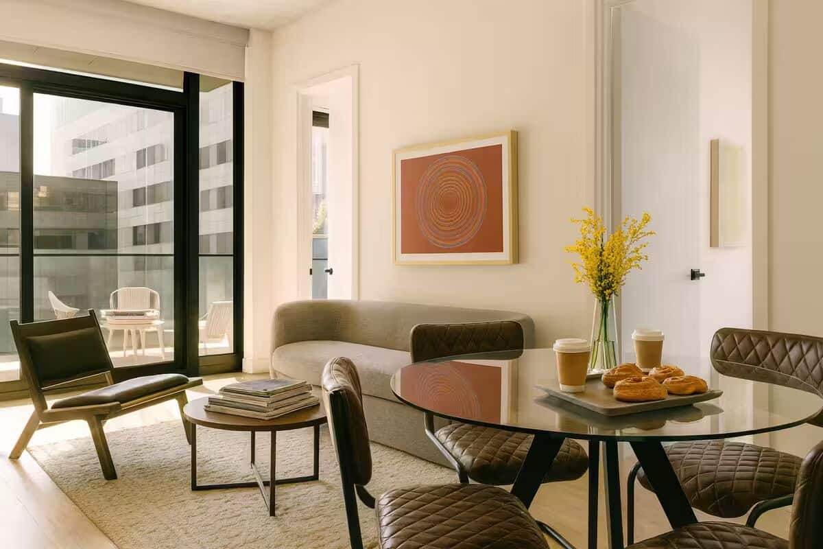 Una sala de estar moderna con una mesa de vidrio, sillones de cuero, un sofá y una mesita de centro con pasteles.