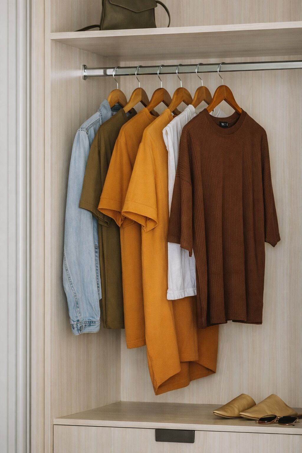A closet with hanging clothes and a pair of shoes on a shelf.
