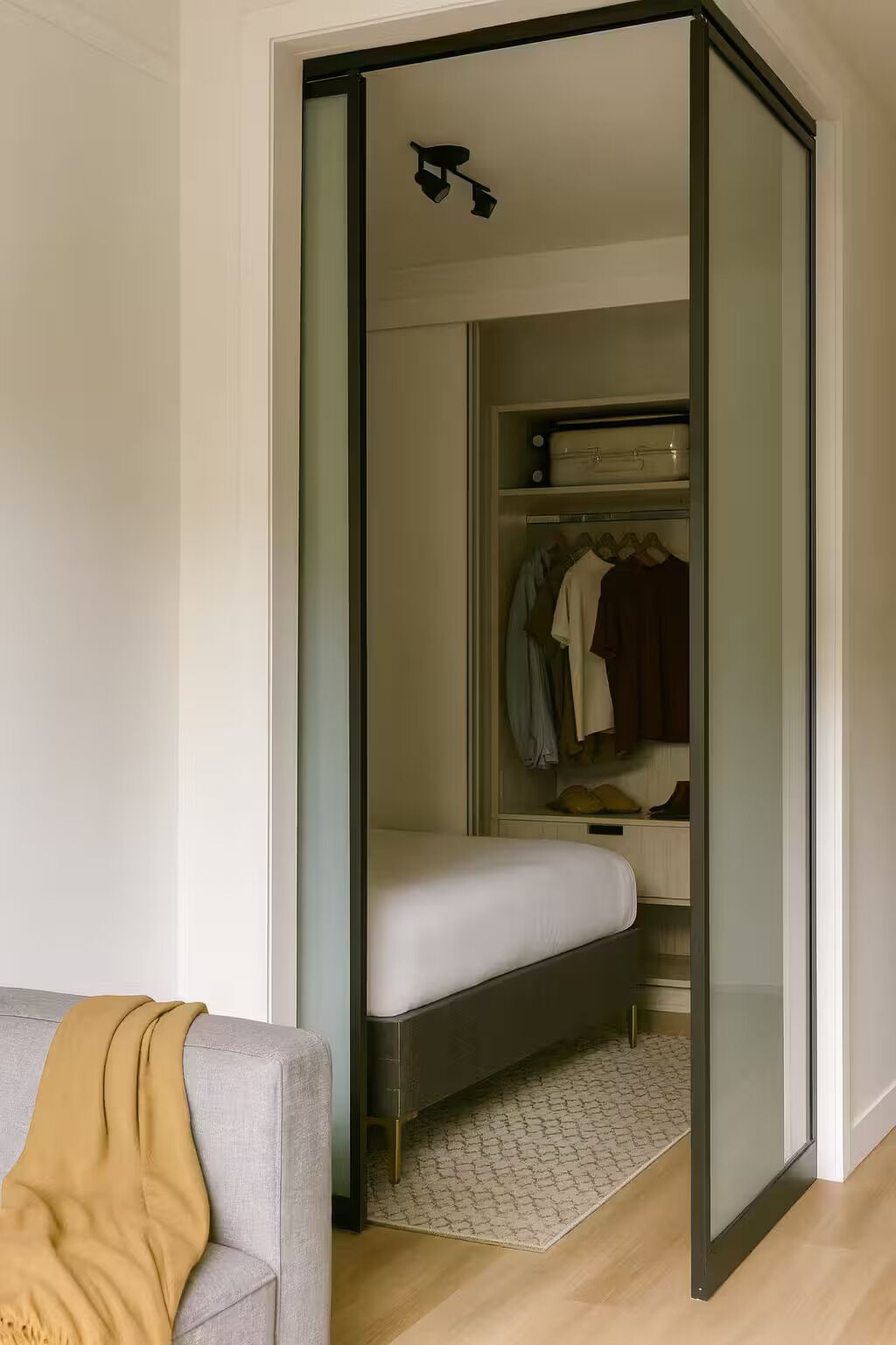 A modern bedroom with a bed, a closet, and a gray sofa.