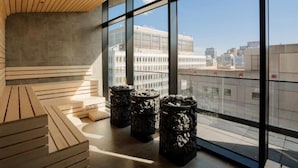 Un intérieur moderne avec de grandes fenêtres, un plafond en bois et un coin salon offrant une vue sur le paysage urbain.