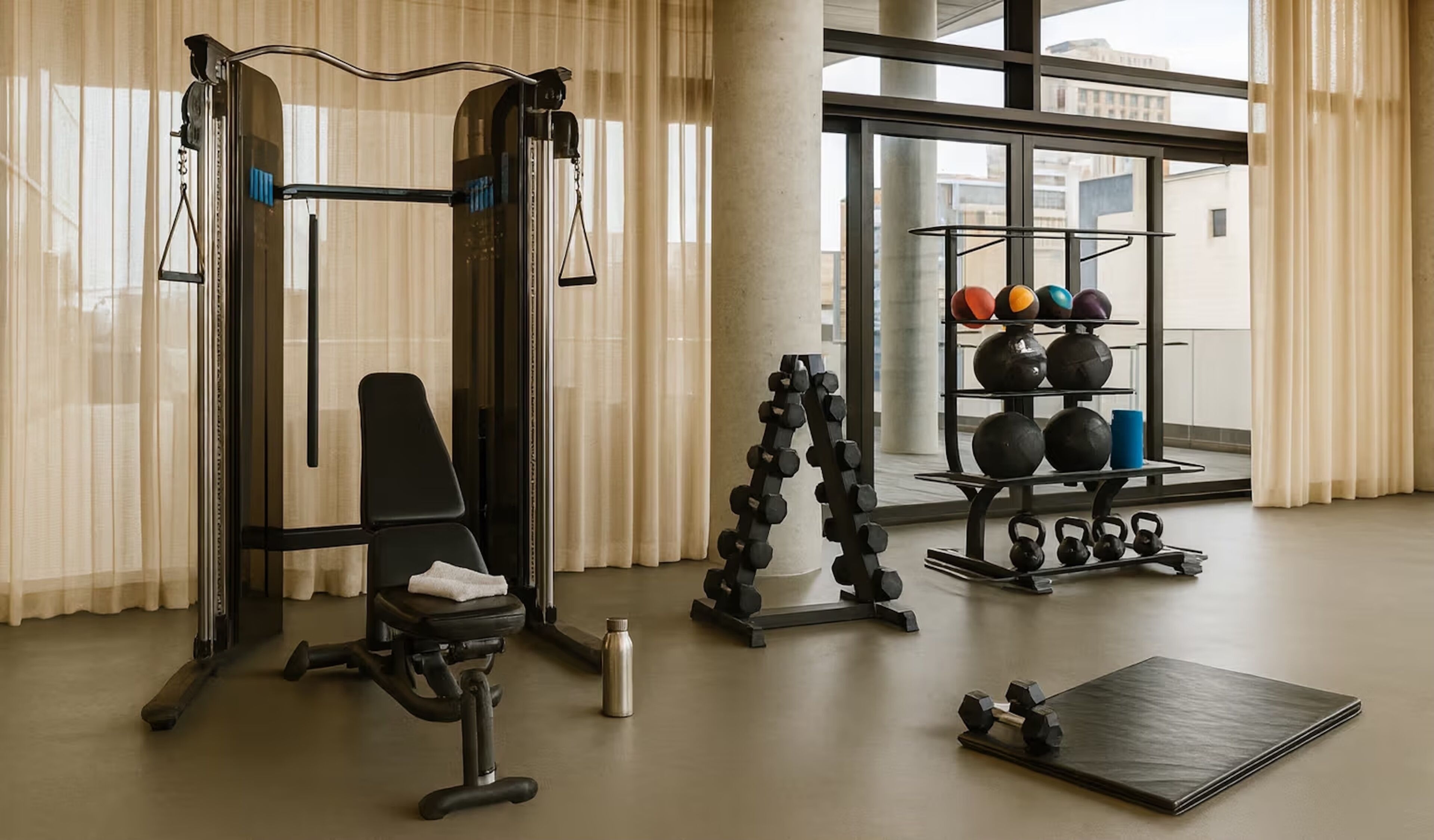 Ett gym med en bänkpress, ett knäböjsställ, kettlebells och hantlar.