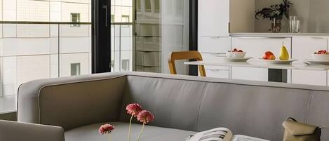 Ein modernes Wohnzimmer mit einem grauen Sofa, einem Laptop, einer Blumenvase und einem Buch.