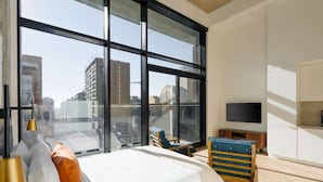 Une chambre d’hôtel moderne dotée d’une grande fenêtre, d’un lit, d’une télévision et d’un coin salon.