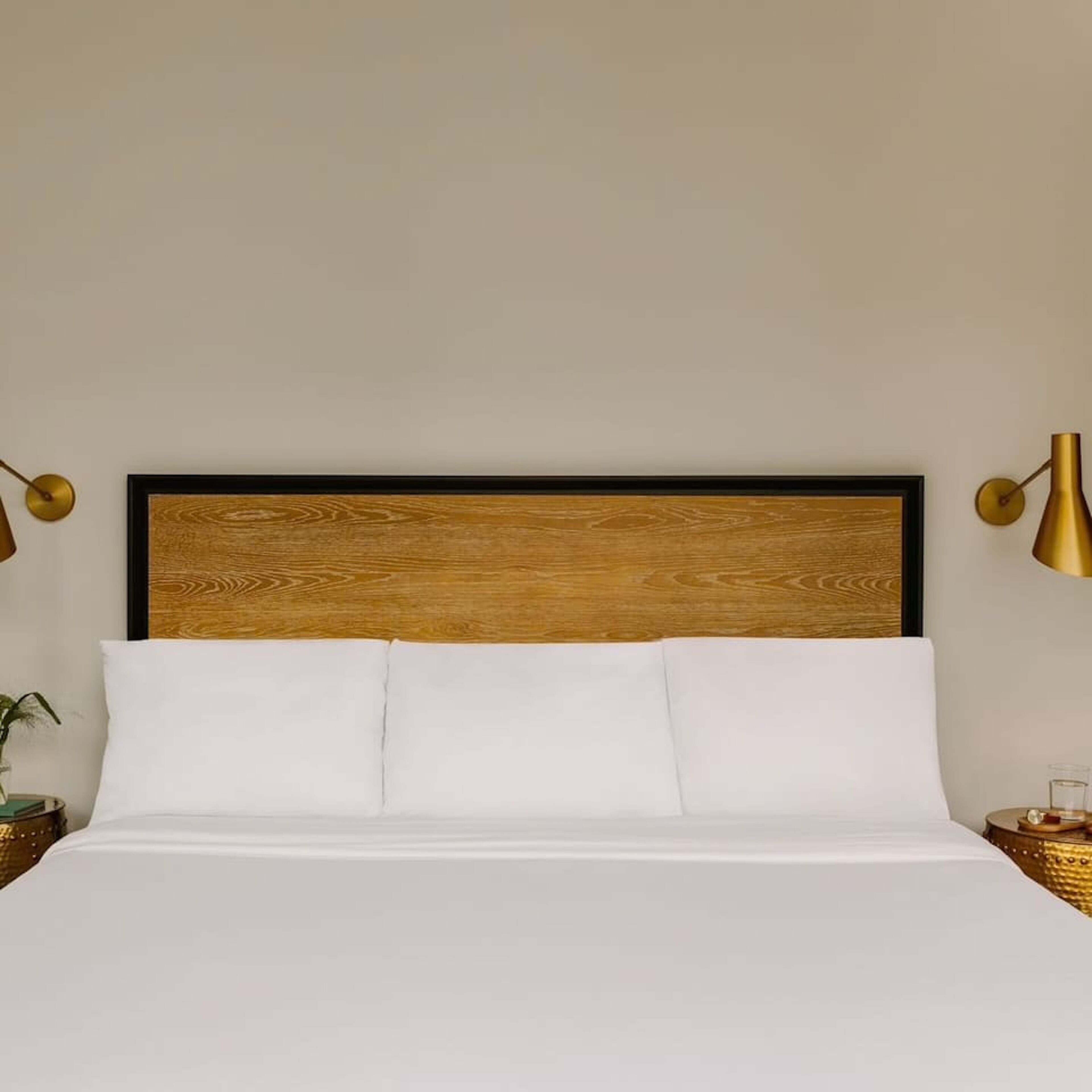 Un lit avec une tête de lit en bois, une literie blanche et deux tables de chevet avec des lampes.