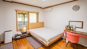 A bedroom with a bed, a desk with a chair, a window, and a wall clock. - Jeju Supgol Dokchae Pension (Jeju City)