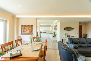 Un coin repas avec une table dressée pour quatre personnes, une cuisine en arrière-plan et un salon avec un canapé.