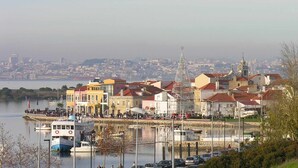 A waterfront cityscape with buildings, a dock with boats, and a prominent church spire. - Family Comfort House (Cavaquinhas)