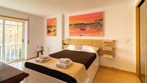 A bedroom with a bed, a bedside table, a window, and two paintings on the wall. - Family Comfort House (Cavaquinhas)