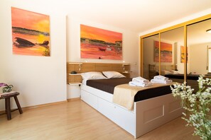 Une chambre à coucher avec un lit, des tables de chevet, un miroir et deux tableaux accrochés au mur.