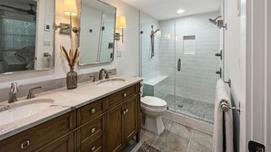 Een moderne badkamer met een dubbele wastafel, toilet en een douchecabine met glazen wanden.