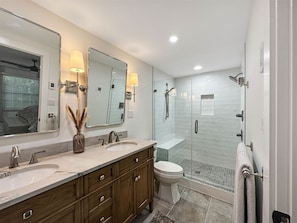 Un bagno moderno con doppio lavabo, un water e una cabina doccia in vetro.