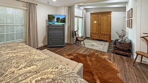 Een slaapkamer met een bed, een dressoir, een televisie en een kledingkast.