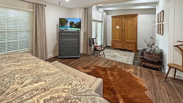 Een slaapkamer met een bed, een dressoir, een televisie en een kledingkast.