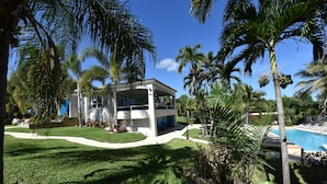 A modern house with a swimming pool, surrounded by palm trees and a well-maintained lawn.