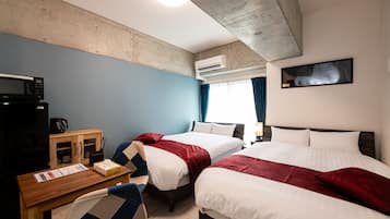 Habitación de hotel con dos camas, un escritorio con microondas, cafetera y televisor.
