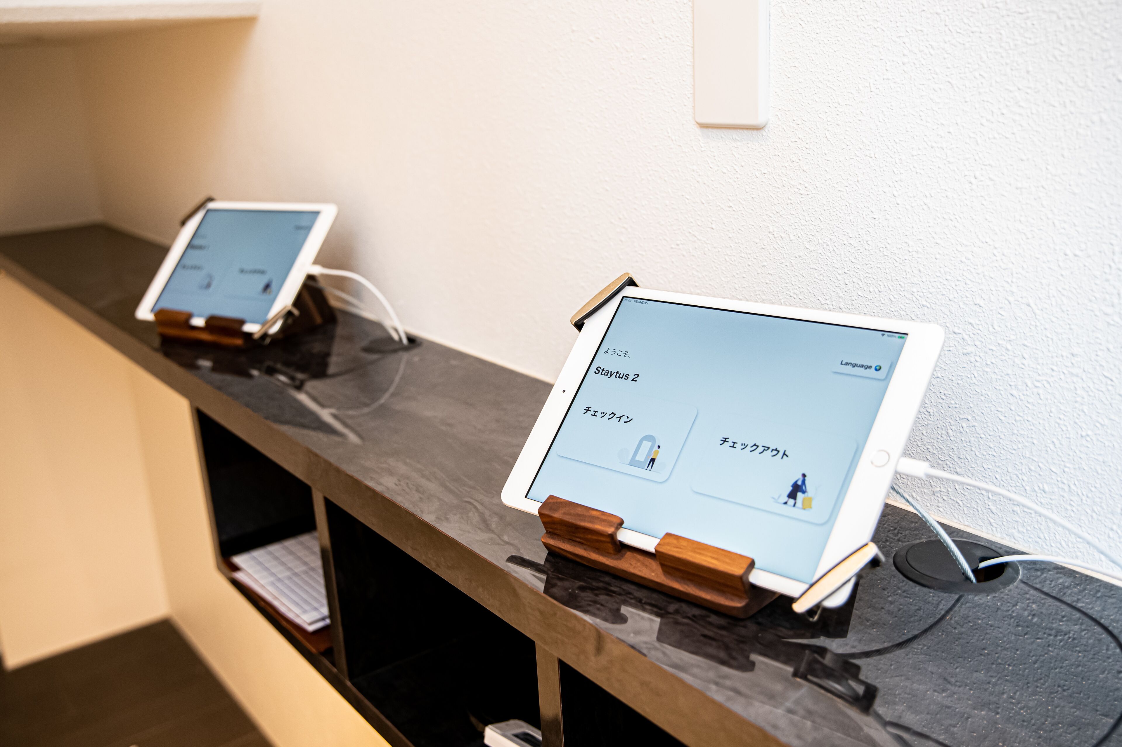 Two tablet devices on a counter with a wooden stand, displaying a language learning application.