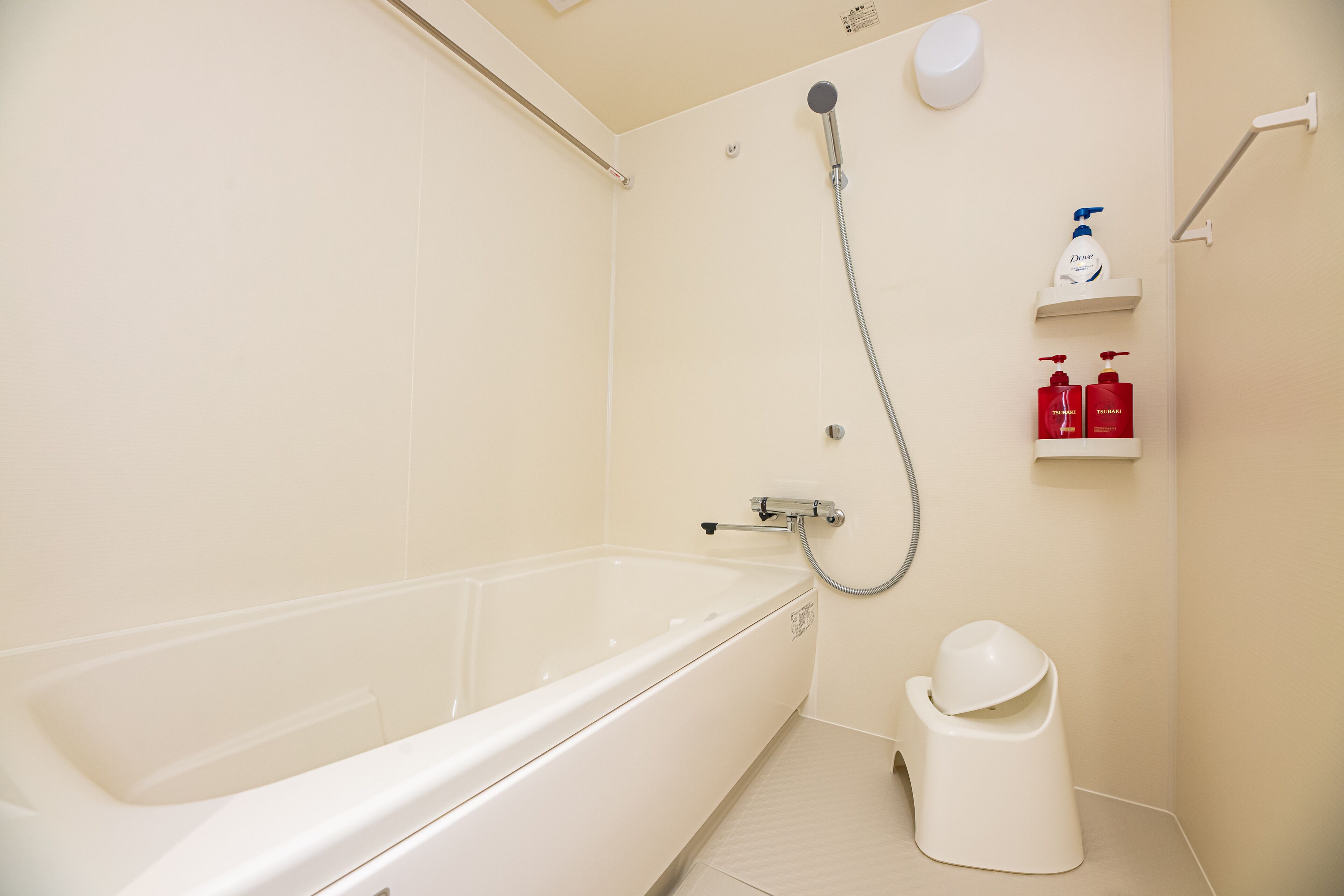 A bathroom with a bathtub, a shower, and a toilet. There are two red bottles on a shelf.