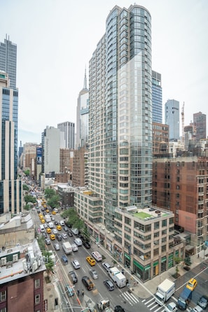 A high-rise building with a curved glass facade, surrounded by other tall buildings and a busy street below.