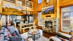 A spacious log cabin with a dining area, kitchen, and a fireplace. - Family-Friendly• Stunning Views • 7 Mi to Dollywood •Hot Tub• Highly Rated! (Sevierville)