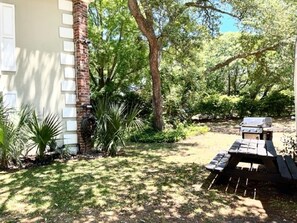 A backyard with a barbecue area, a brick pillar, and various plants. - Ocean tranquility 2 br house  free parking prime location downtown Myrtle Beach (Myrtle Beach)