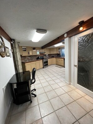 A kitchen with a dining area, featuring a black dining table with chairs, a stove, and a refrigerator. - Ocean tranquility 2 br house  free parking prime location downtown Myrtle Beach (Myrtle Beach)