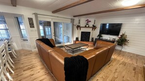 A living room with a brown leather sofa, a coffee table, a fireplace, and a TV mounted on the wall. - Indoor Pool , Hot Tub, Game Room & Gym  (South Jordan)