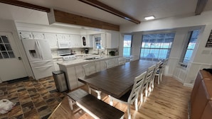 A modern kitchen with white cabinetry, a wooden dining table, and a bench. - Indoor Pool , Hot Tub, Game Room & Gym  (South Jordan)