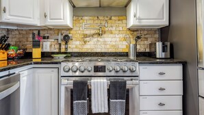 A kitchen with white cabinets, a stainless steel stove, and a tiled backsplash. - Backyard fishing & birdwatching - 3,600sqft home near beach w/ hot tub, gazebo (Corpus Christi)