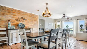 A dining area with a brick wall, white cabinets, and a chandelier. - Backyard fishing & birdwatching - 3,600sqft home near beach w/ hot tub, gazebo (Corpus Christi)