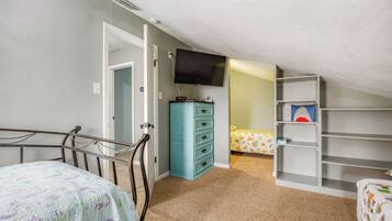 Cozy bedroom with a single bed, dresser, TV, and shelf unit.