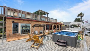 A wooden deck with outdoor seating, a hot tub, and a covered patio area. - Backyard fishing & birdwatching - 3,600sqft home near beach w/ hot tub, gazebo (Corpus Christi)