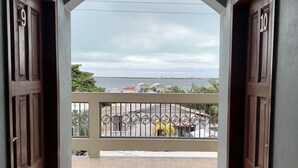 Placa de saída acima de uma porta que dá para uma varanda com vista para o mar e edifícios.
