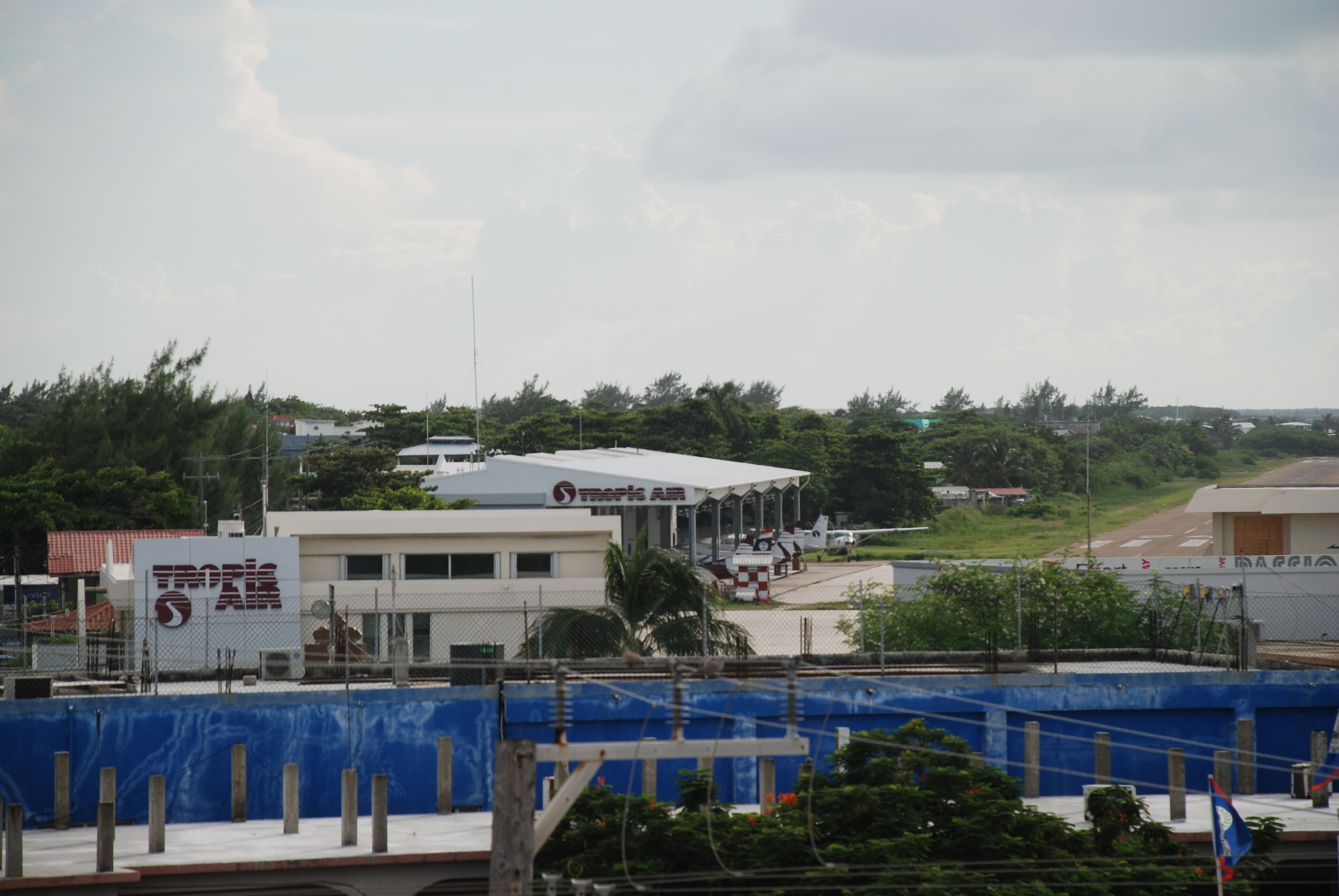 A commercial building with a covered outdoor area, a fenced construction site, and a clear sky.