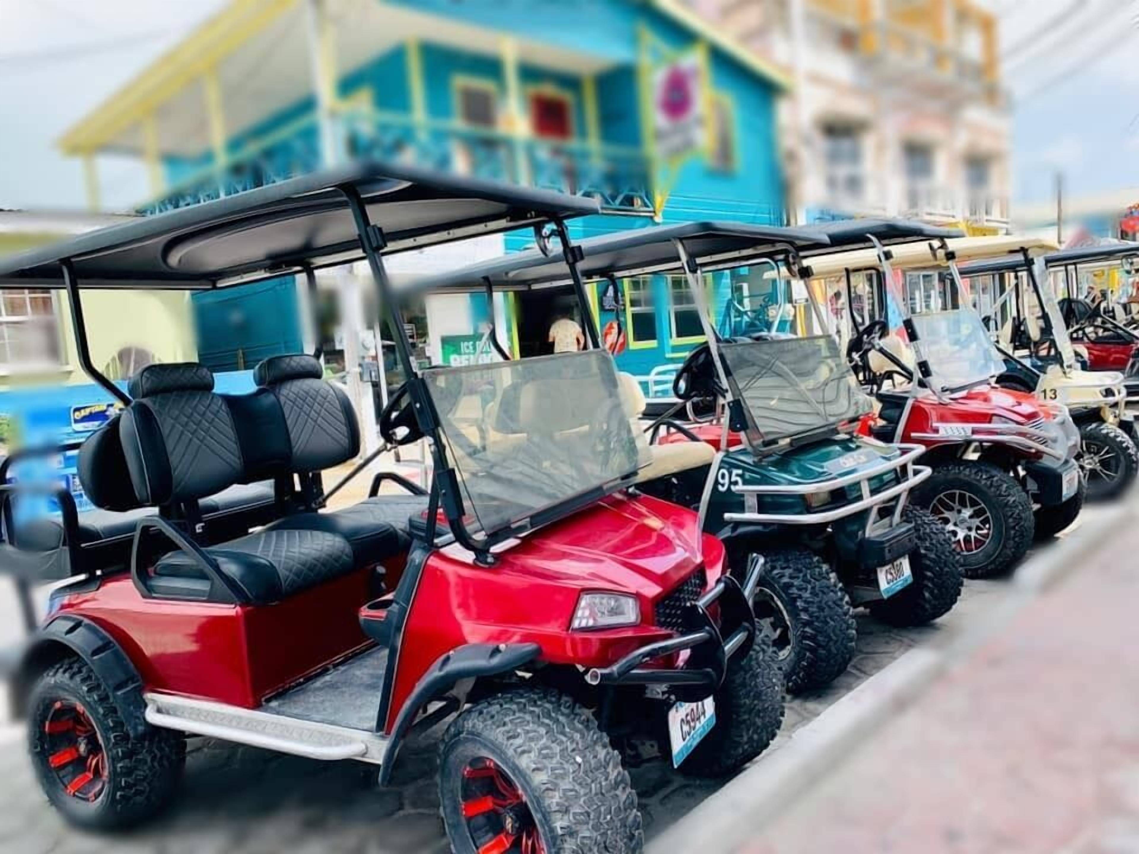 A row of golf carts parked in front of a building with a blue facade and a sign that reads "ICE CREAM".